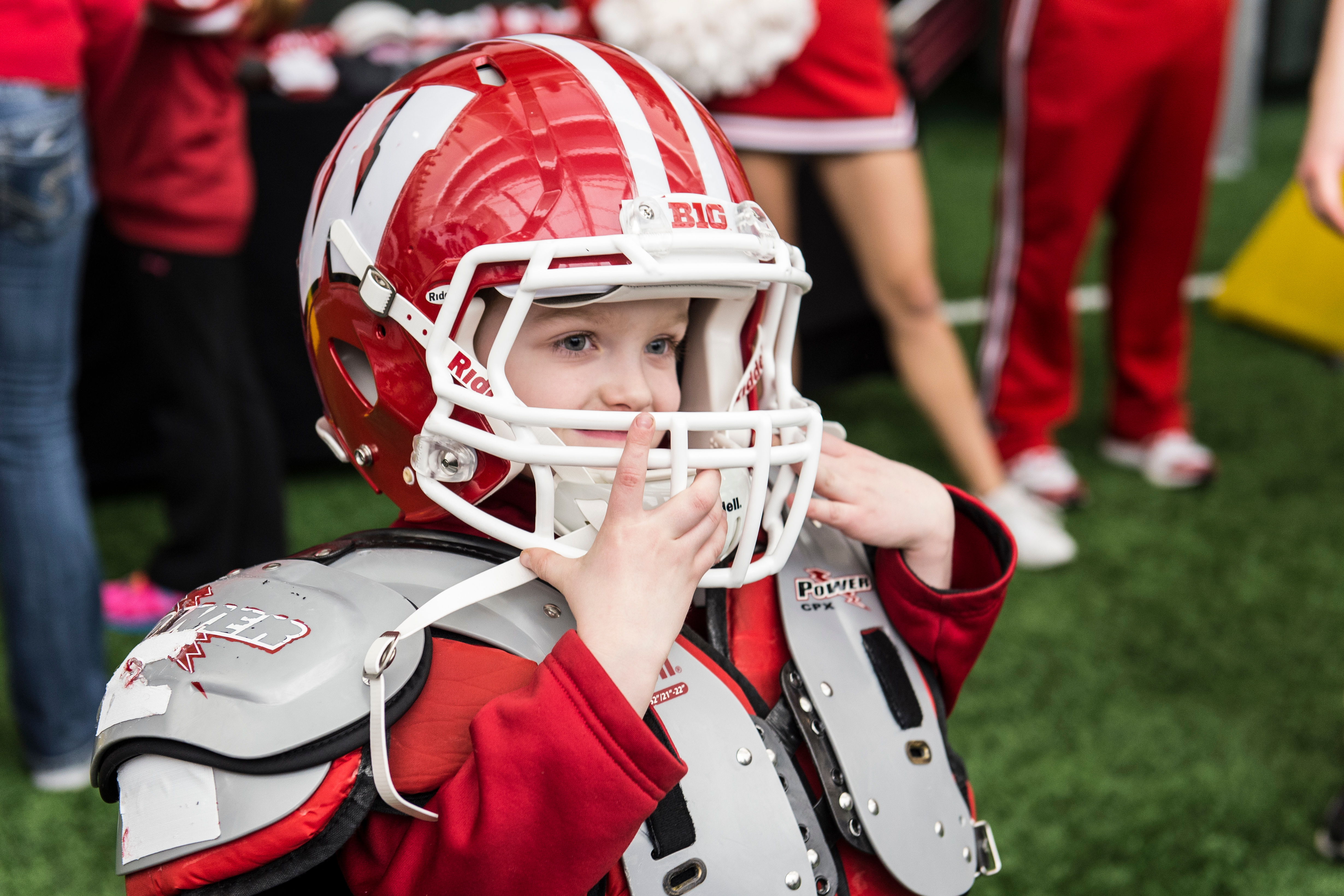 little boy wearing badger football uniform and helmet