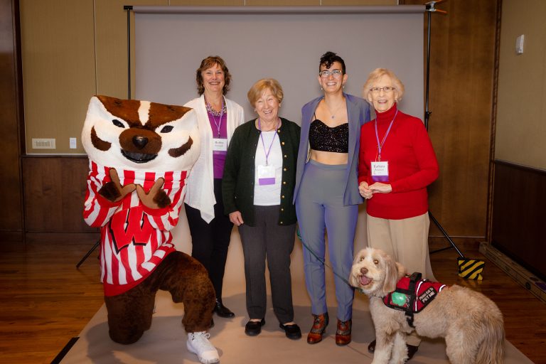 Returning adult student with guide dog, donors, and Bucky.