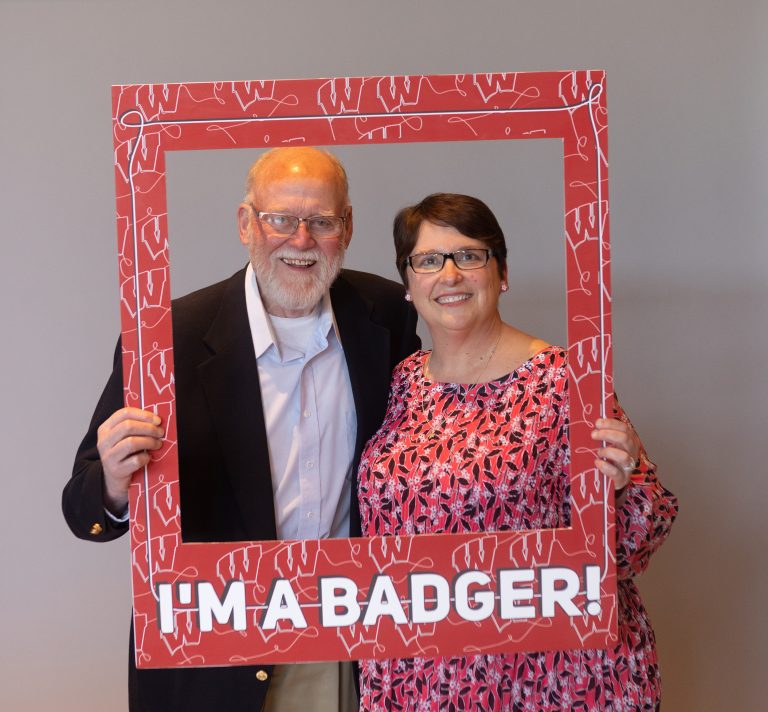 Returning adult student and guest looking through a frame with the words, "I'm a badger."